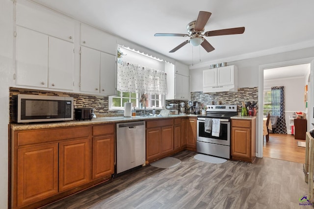 kitchen featuring a wealth of natural light, dark wood-type flooring, stainless steel appliances, and ornamental molding