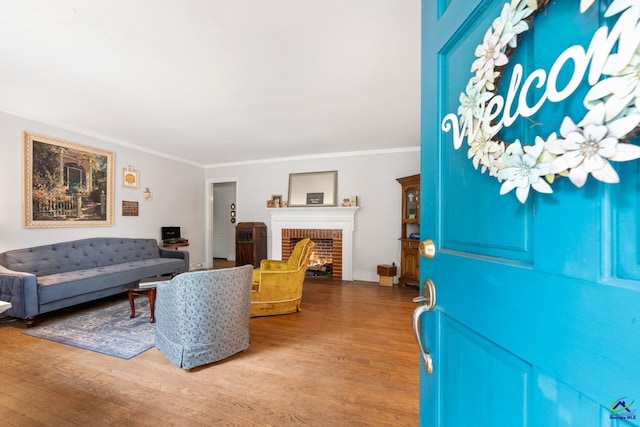 living room with hardwood / wood-style floors, crown molding, and a brick fireplace