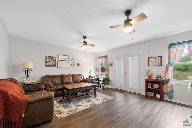 living room featuring ceiling fan, french doors, a textured ceiling, and hardwood / wood-style flooring