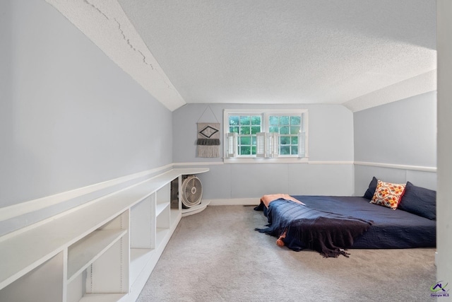 carpeted bedroom with a textured ceiling and vaulted ceiling