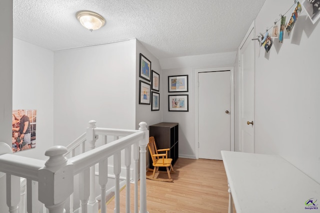 bedroom featuring light hardwood / wood-style floors, a textured ceiling, and a nursery area