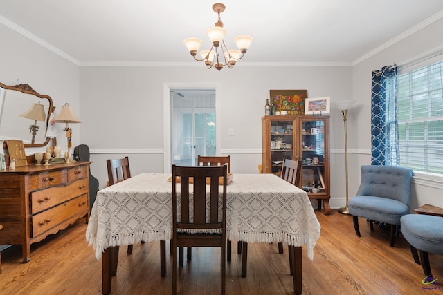 dining space featuring hardwood / wood-style floors, a healthy amount of sunlight, crown molding, and a chandelier