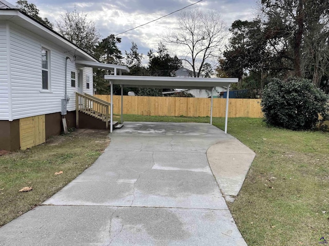 view of yard featuring concrete driveway and fence