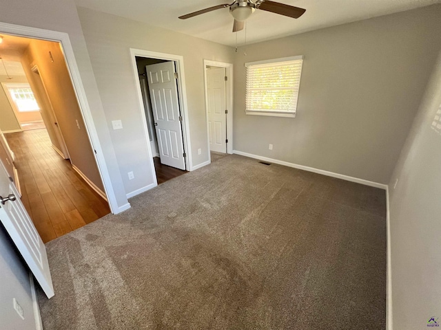 unfurnished bedroom with ceiling fan and dark colored carpet