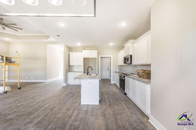 kitchen featuring sink, dark hardwood / wood-style flooring, an island with sink, light stone countertops, and white cabinets