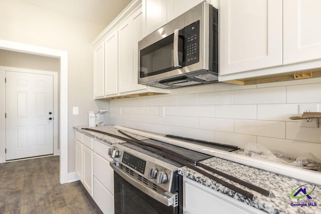 kitchen featuring dark hardwood / wood-style floors, tasteful backsplash, white cabinets, oven, and light stone countertops