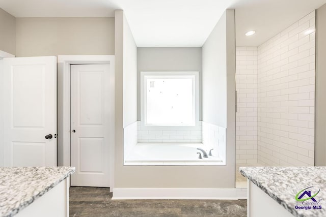 bathroom with vanity, a bathing tub, and wood-type flooring