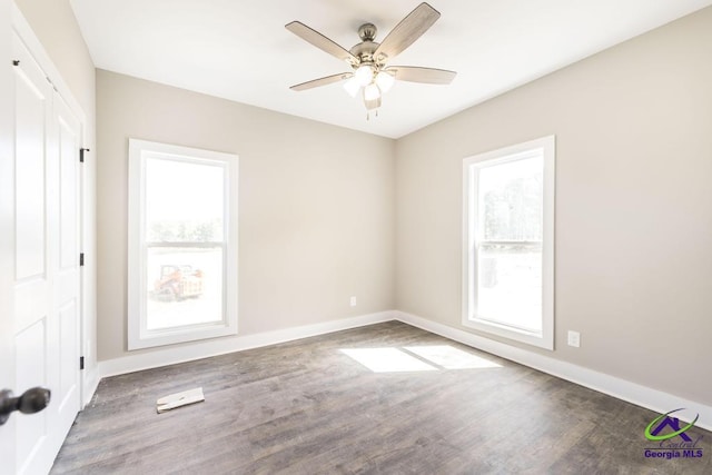 unfurnished room featuring dark wood-type flooring, plenty of natural light, and ceiling fan