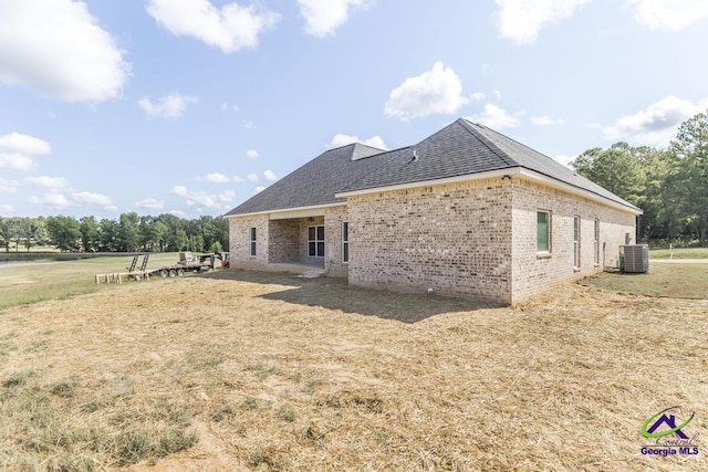 rear view of property featuring a lawn and central air condition unit