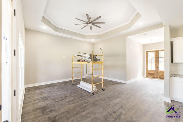 workout area featuring dark wood-type flooring, ornamental molding, and a raised ceiling