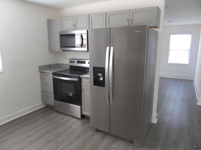 kitchen with gray cabinets, light wood-type flooring, and appliances with stainless steel finishes