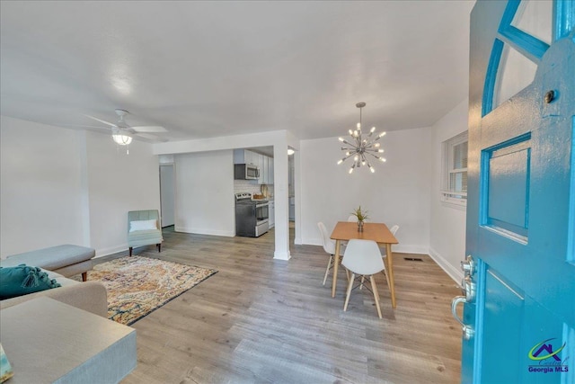 dining space with light hardwood / wood-style flooring and ceiling fan with notable chandelier