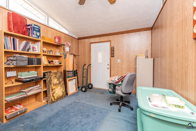 office featuring carpet flooring, ceiling fan, wooden walls, and vaulted ceiling