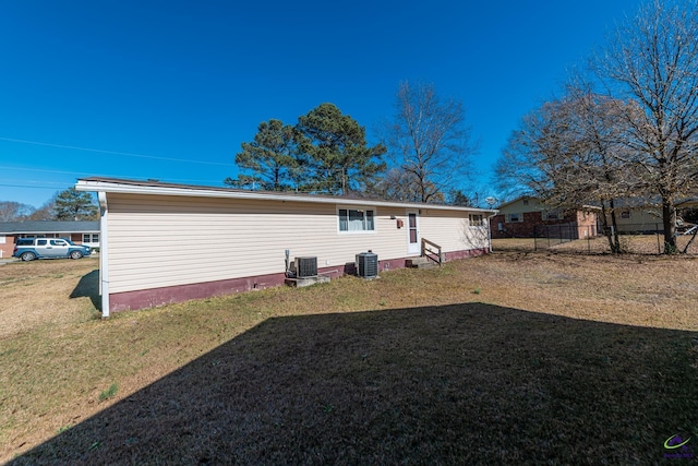 rear view of property featuring a yard and central AC unit