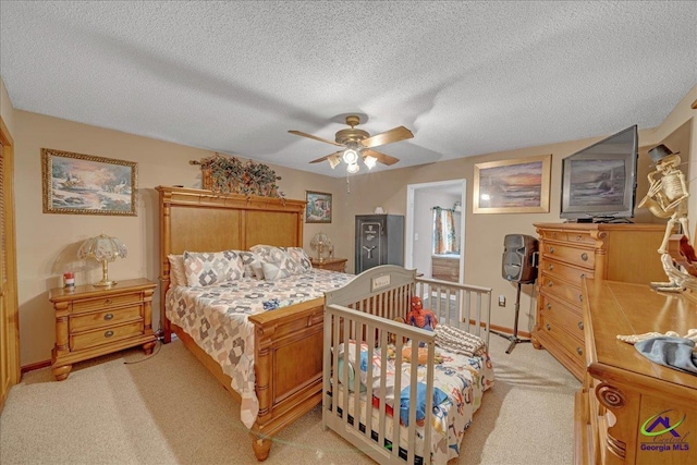 bedroom featuring a textured ceiling, light colored carpet, and ceiling fan