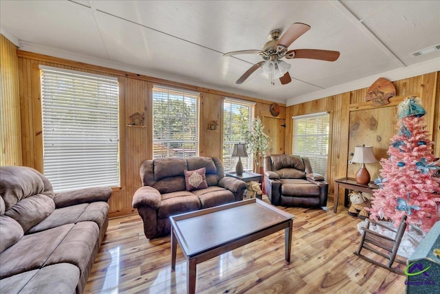 living room featuring light hardwood / wood-style flooring, ceiling fan, and wooden walls