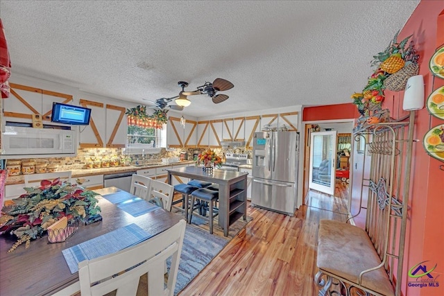 kitchen featuring ceiling fan, sink, stainless steel appliances, a textured ceiling, and light wood-type flooring