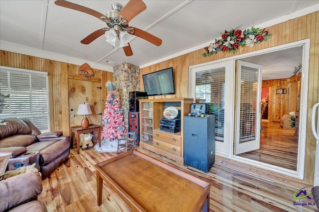 living room with hardwood / wood-style floors, plenty of natural light, wood walls, and ceiling fan