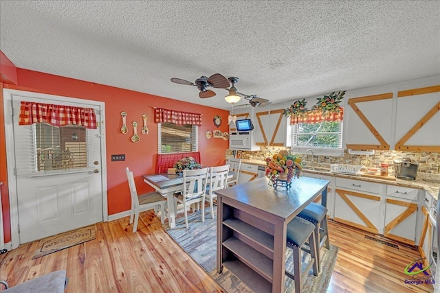 dining area featuring a textured ceiling, ceiling fan, light hardwood / wood-style floors, and sink