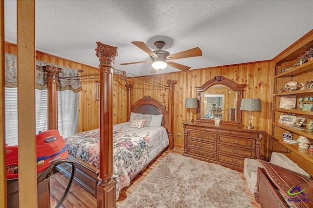 bedroom featuring a textured ceiling, ceiling fan, and wooden walls