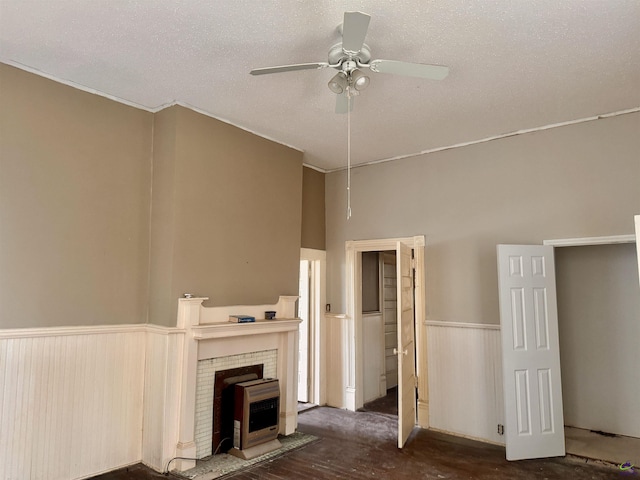 unfurnished living room featuring a textured ceiling, heating unit, a wood stove, and ceiling fan