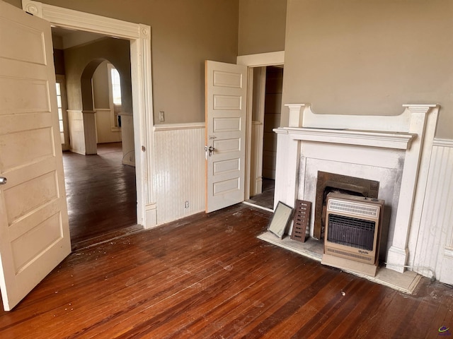 unfurnished living room with heating unit and dark wood-type flooring