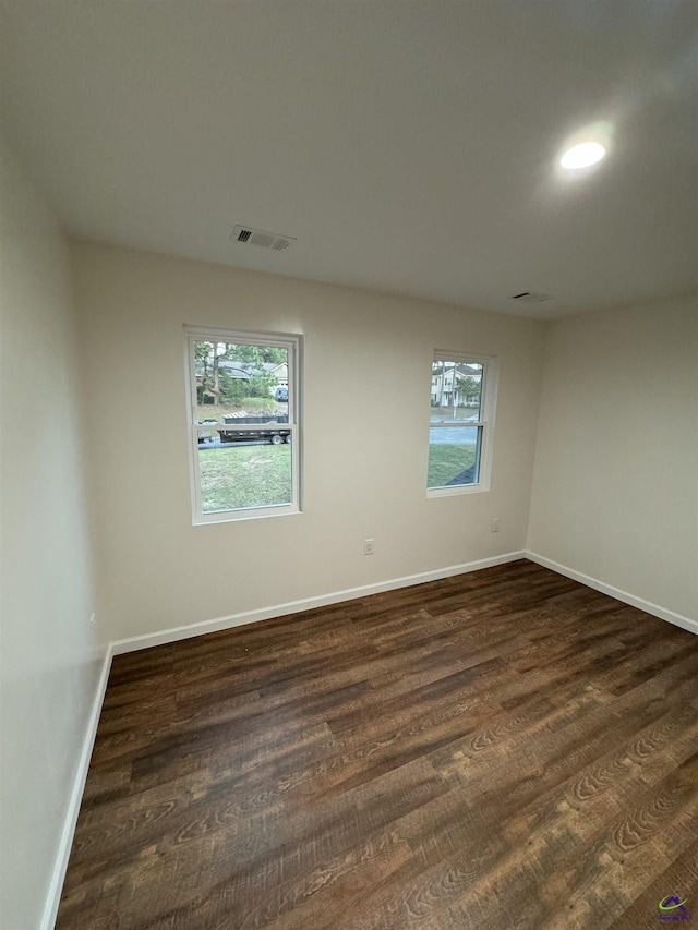 spare room featuring dark hardwood / wood-style flooring and a healthy amount of sunlight