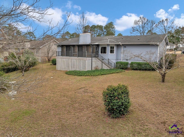 rear view of house featuring a sunroom and a lawn