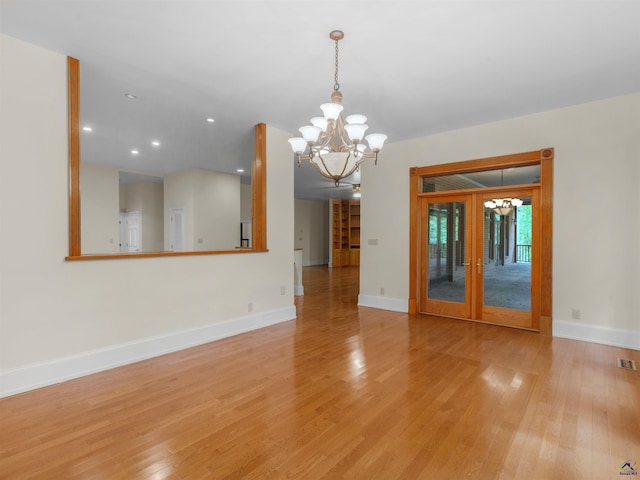 spare room with french doors, light hardwood / wood-style floors, and a notable chandelier