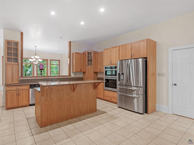 kitchen featuring a center island, an inviting chandelier, hanging light fixtures, appliances with stainless steel finishes, and a kitchen bar