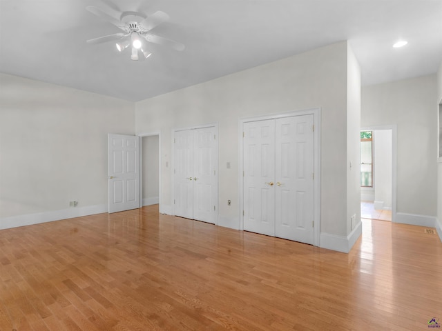 unfurnished bedroom featuring ceiling fan, multiple closets, and light hardwood / wood-style flooring