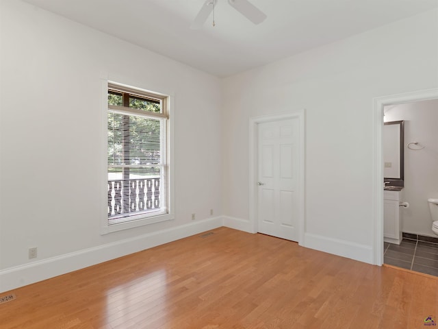 unfurnished bedroom with ceiling fan, wood-type flooring, and connected bathroom