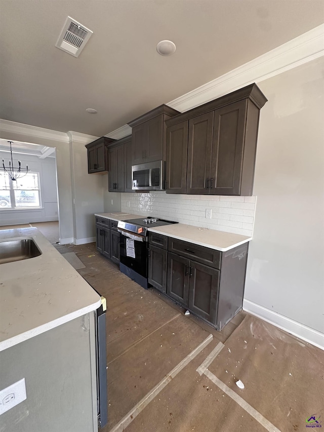 kitchen featuring crown molding, visible vents, backsplash, appliances with stainless steel finishes, and baseboards