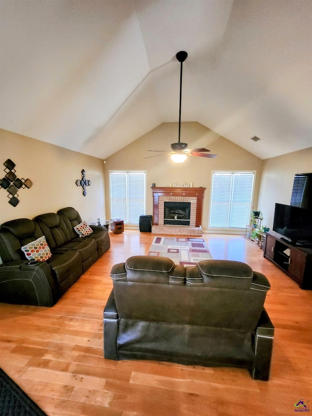 living room featuring a fireplace, ceiling fan, light hardwood / wood-style flooring, and lofted ceiling