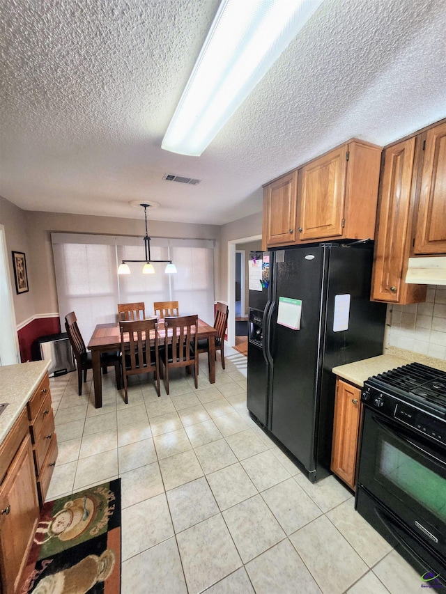 kitchen with decorative backsplash, light tile patterned floors, hanging light fixtures, and black appliances