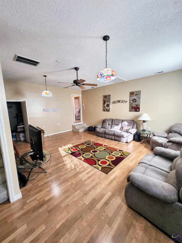 living room featuring ceiling fan, hardwood / wood-style floors, and a textured ceiling