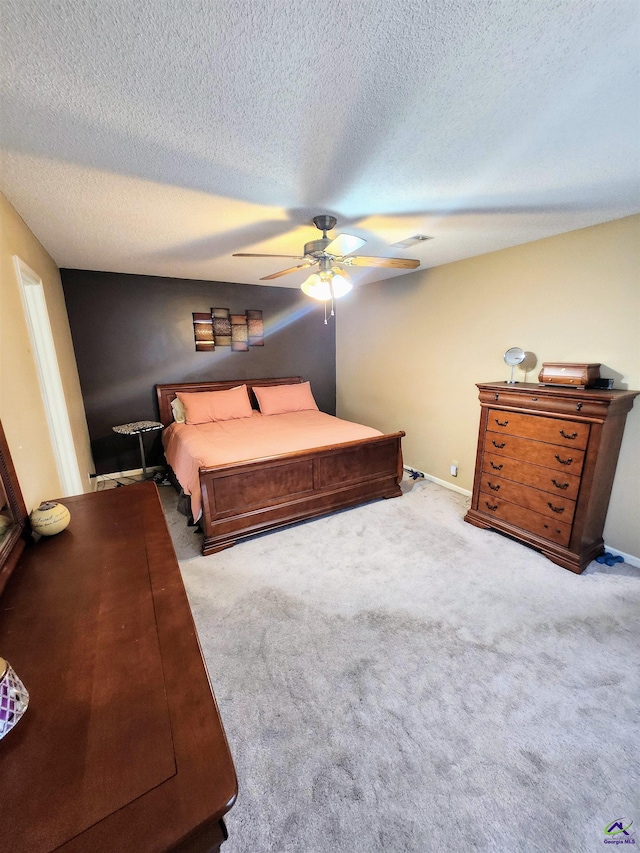 carpeted bedroom with ceiling fan and a textured ceiling