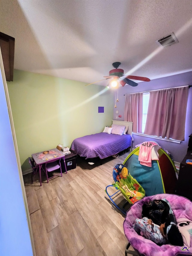 bedroom with a textured ceiling, hardwood / wood-style flooring, and ceiling fan