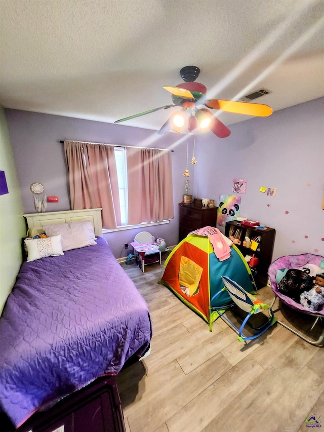 bedroom featuring ceiling fan, wood-type flooring, and a textured ceiling