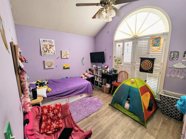 bedroom featuring a textured ceiling, ceiling fan, light hardwood / wood-style floors, and vaulted ceiling