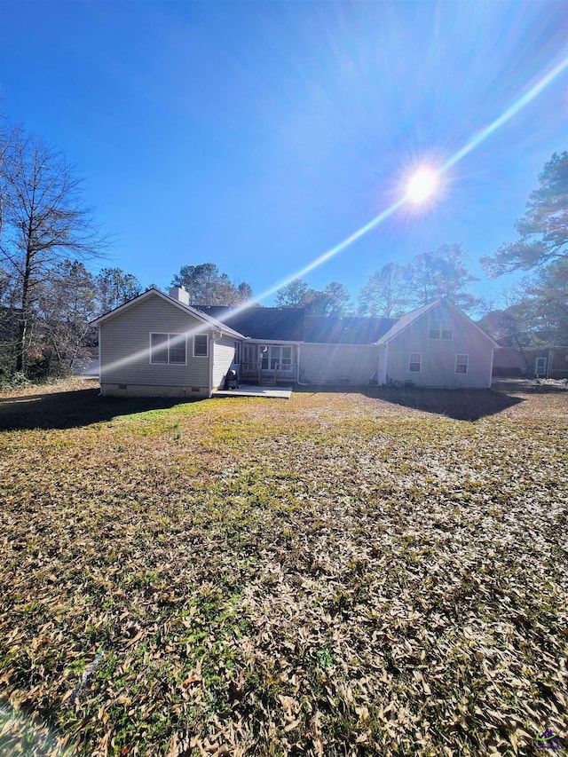 back of property with a mountain view and a yard