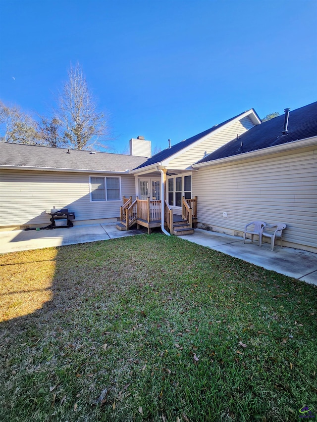 rear view of house featuring a lawn, a deck, and a patio