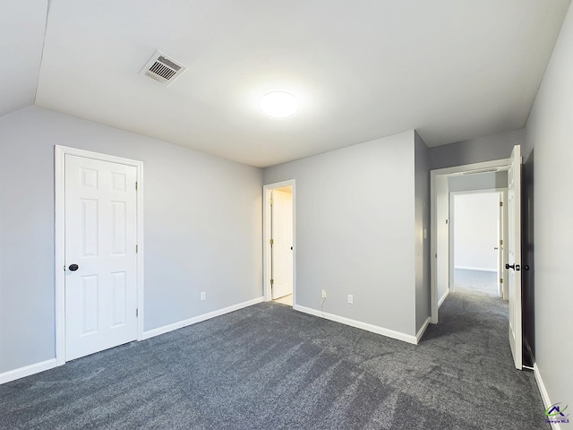 unfurnished bedroom with vaulted ceiling and dark carpet