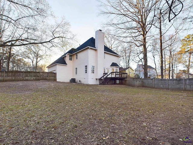 rear view of property featuring a lawn, central AC unit, and a deck