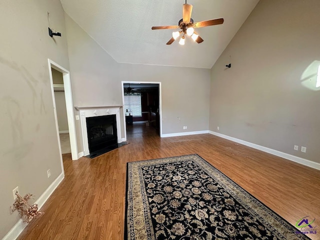 unfurnished living room featuring ceiling fan, a premium fireplace, hardwood / wood-style flooring, a textured ceiling, and high vaulted ceiling