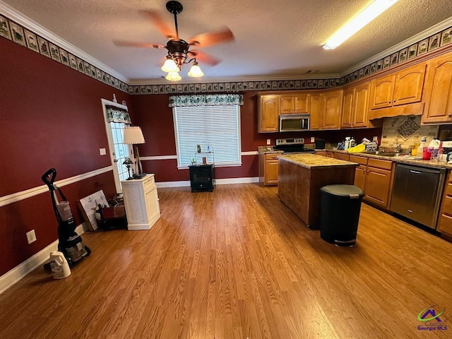 kitchen with a textured ceiling, appliances with stainless steel finishes, hardwood / wood-style flooring, and a center island