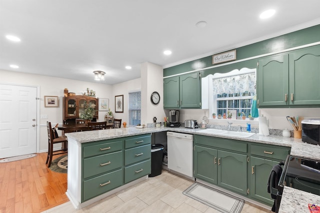 kitchen with stove, white dishwasher, green cabinetry, and sink