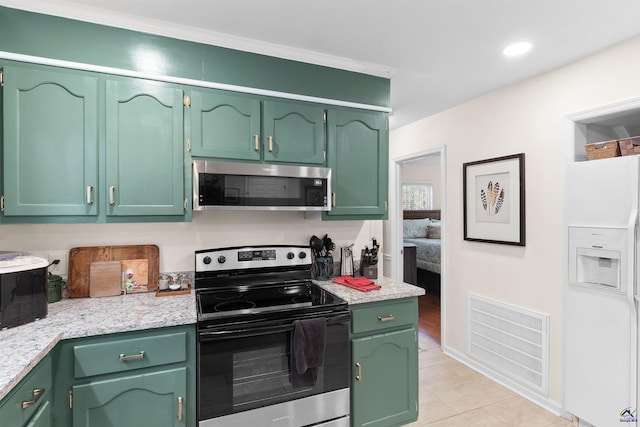 kitchen featuring light stone counters, light tile patterned floors, green cabinetry, and appliances with stainless steel finishes