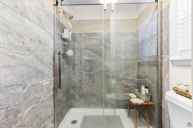 bathroom featuring a shower with shower door and toilet