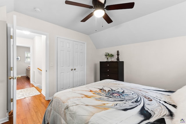 bedroom featuring ceiling fan, lofted ceiling, wood-type flooring, and a closet